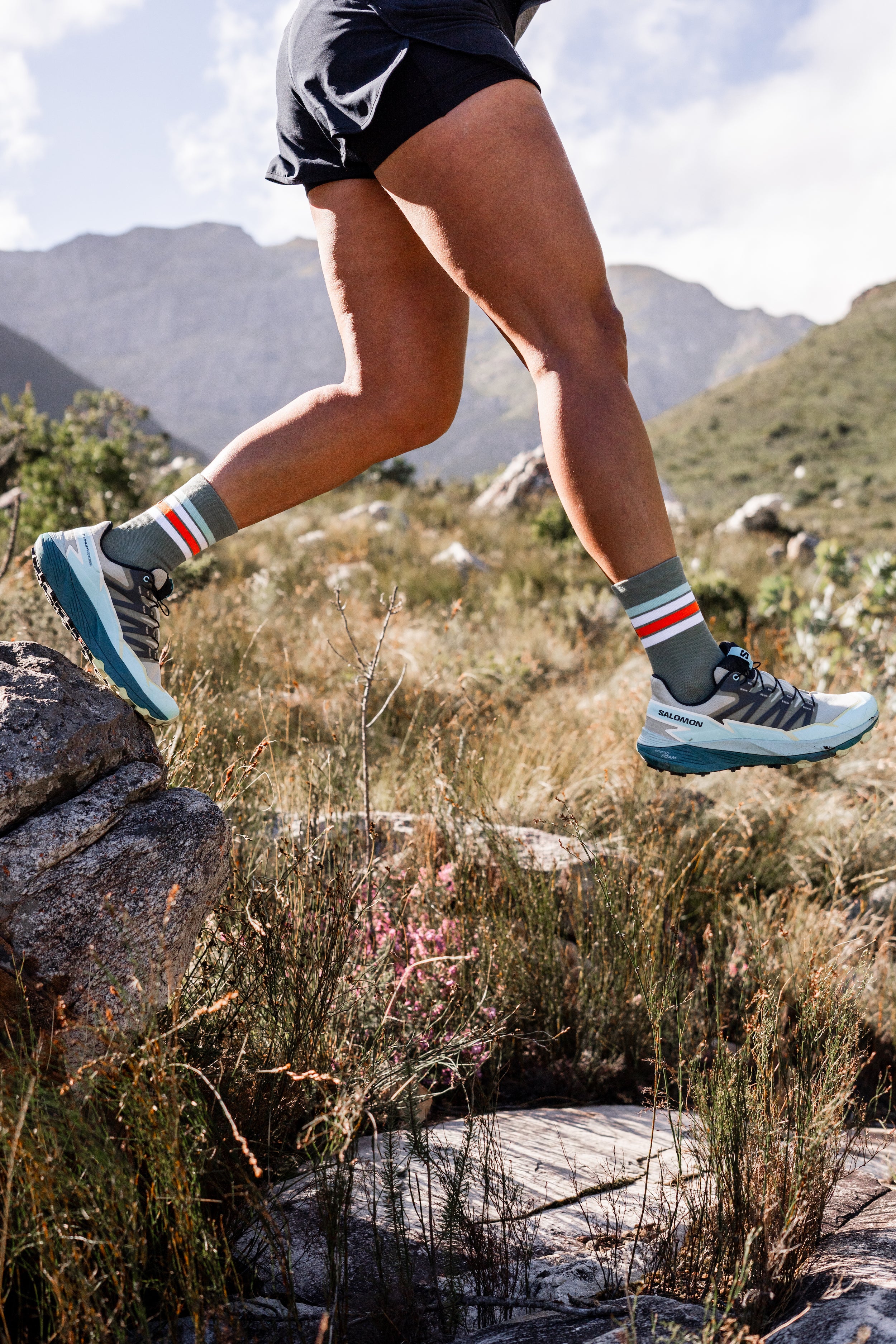 Person running on a rocky trail with mountains in the background