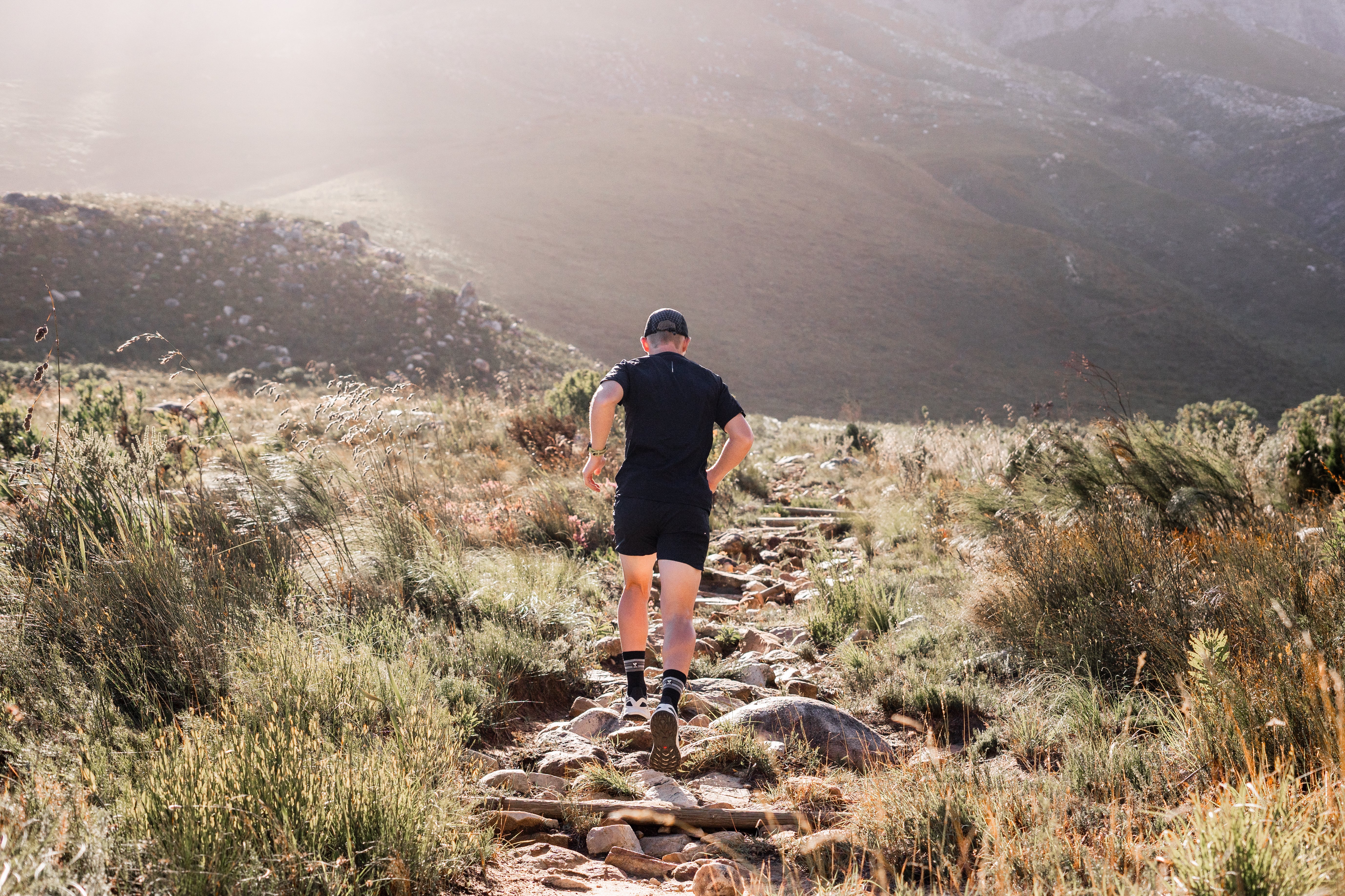 Person running on a rocky trail in a mountainous landscape